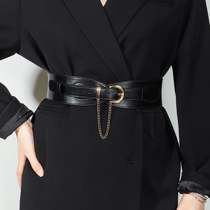 Detail of a wide black leather waist belt with gold buckle and chain on a blazer