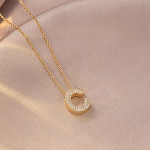 Close-up of gold necklace featuring letter C pendant paved with sparkling zircons