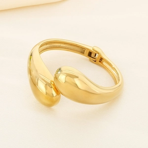 Detail of golden teardrop bangle featuring a sleek hinge closure and polished finish