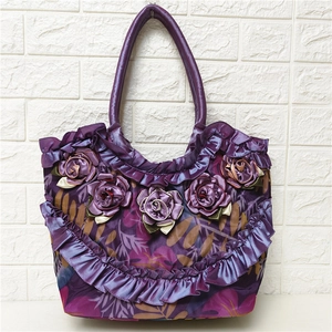 Close-up of purple silk handbag featuring 3D rose flowers and layered ruffle details