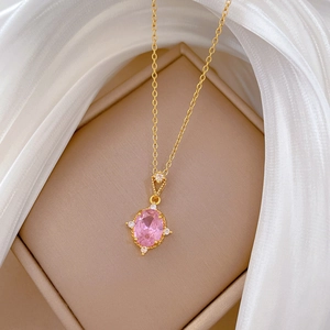 Close-up of a gold necklace featuring a pink oval gemstone pendant with small diamonds