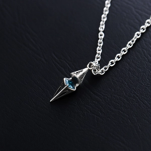 Macro shot of silver starburst pendant with a blue gemstone on dark leather background