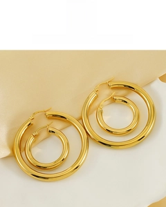 Detail of high-polished 18K gold plated hoop earrings on champagne silk fabric