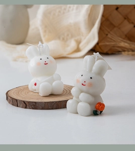 Detail view of two cute white rabbit candles on a wooden base with lace and rattan decor