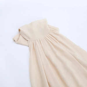 Detail showing elegant accordion pleats on the neckline of a beige chiffon dress