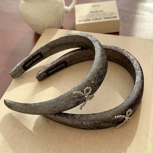 Elegant wide grey sparkling hairbands with silver bead bow detail in a cozy home setting