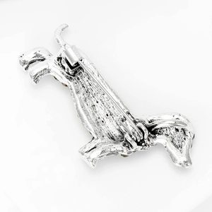 Macro detail of the silver alloy puppy brooch showing metal texture and pin attachment