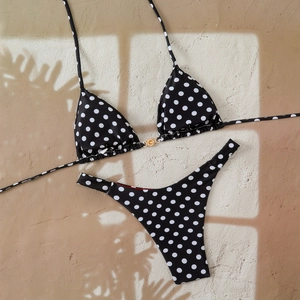 Detail of polka dot bikini top with gold sun ornament and adjustable tie straps