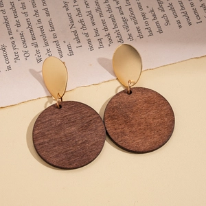 Detail of vintage gold metal and dark brown wood disc earrings on a retro book page