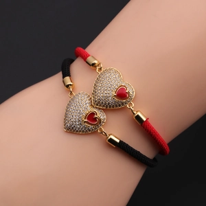 Detailed macro of red and black enamel heart charms on adjustable woven bracelets