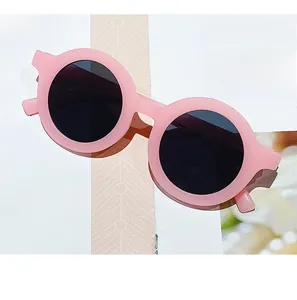 Detail of pink matte round sunglasses for kids with dark grey lenses on a magazine page