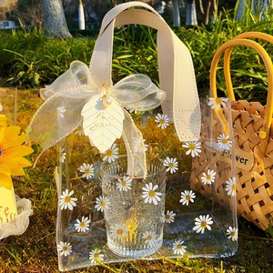 Clear PVC daisy gift bag with cream leather handle and white ribbon bow on grass