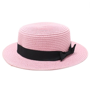 Detail of pink straw boater hat featuring a black ribbon band and side bow tie