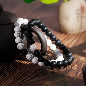 Matte black onyx and white marble stone beaded bracelets hanging on a dark ceramic teapot