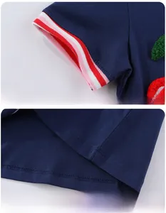 Détail de la robe tricotée bleu foncé avec broderie cerise et poignets rayés