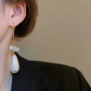 Détail d'une boucle d'oreille grosse perle goutte et fleur en zircon argenté sur modèle