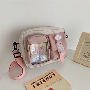 Detail of canvas crossbody bag showing transparent card pocket and cute rocket buckle