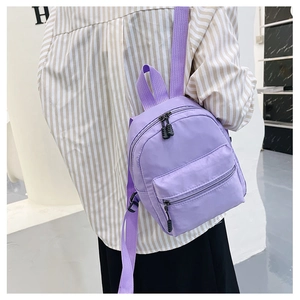 Rear view of a model wearing a mini purple nylon backpack with adjustable straps