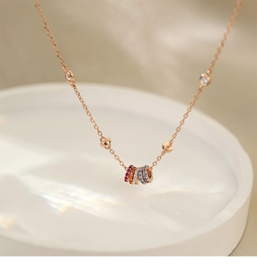 Detail of rose gold necklace with rainbow zircon rings and clear stones in macro shot