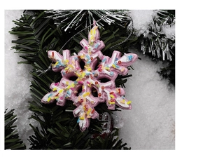 Detailed view of pink snowflake Christmas ornament with colorful beads on pine branch