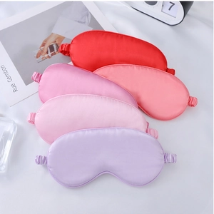 Flat lay of multiple satin silk sleep masks in red, pink and purple on white fabric