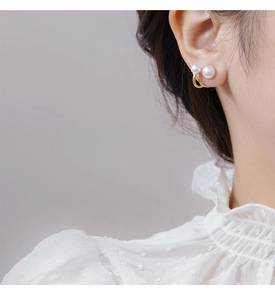 Close-up of double pearl earrings in gold finish worn for a minimalist elegant style