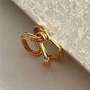 Minimalist S925 sterling silver knot ring in golden finish on a grey stone surface