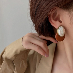 Vintage round geometric stud earrings with faux leather and pearls worn by a model