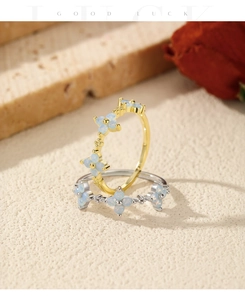 Detailed close-up of gold and silver clover rings with opal inlay on stone background