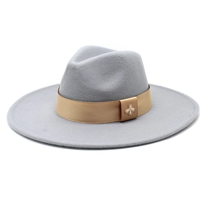 Detail of grey wool felt fedora featuring a champagne ribbon and gold bee brooch