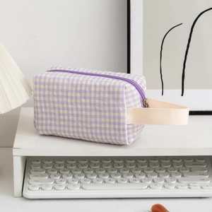 Detail of quilted purple gingham toiletry bag with woven handle and smooth metal zipper
