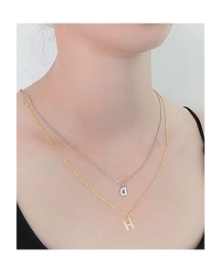 Detail of layered gold and silver necklaces with micro-pave cubic zirconia letter pendants
