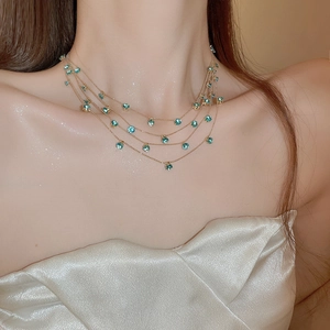 Detail einer mehrlagigen Goldkette mit funkelnden blauen Zirkonia-Anhängern
