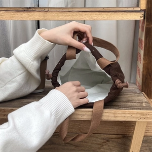 Detailed interior of brown wool drawstring handbag showing white fabric lining and capacity