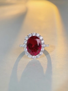Macro shot of oval red ruby ring in S925 silver with sparkling white zircon halo