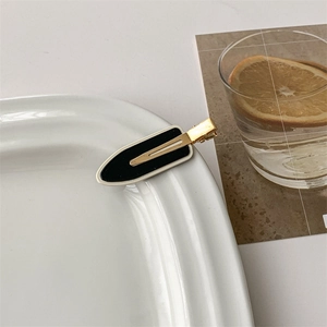 Detail of checkered black and white hair clip on a decorative white ceramic plate