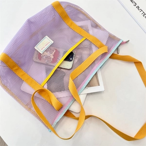 Détail du sac de plage en filet violet avec sangles jaunes et grand espace de rangement