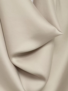 Gros plan sur le tissu en satin beige montrant le tissage fin et la texture soyeuse