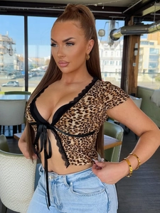 Detail of leopard print crop top featuring black lace trim and front ribbon tie design