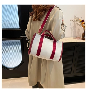 Detail of canvas tote bag in beige and burgundy with wide shoulder strap on a model