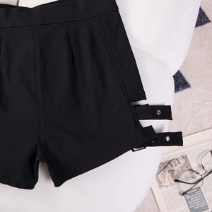Dettaglio dei pantaloncini neri a vita alta con fibbie metalliche e trama in twill