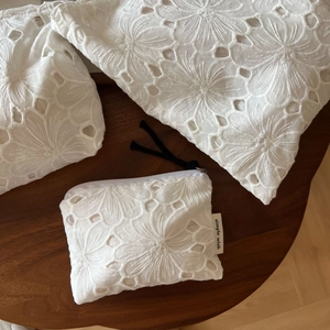 Close-up of white cotton floral embroidery storage bags with zipper and lanyard details