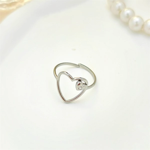 Detail of silver hollow heart ring with small diamond on a ceramic dish