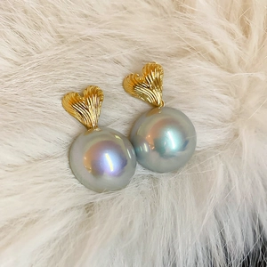 Detailed shot of golden heart stud with large grey pearl on soft white fur background