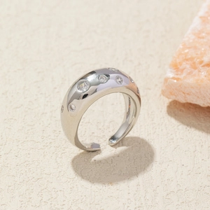 Close-up of polished silver wide ring with irregular surface and inlaid zircons
