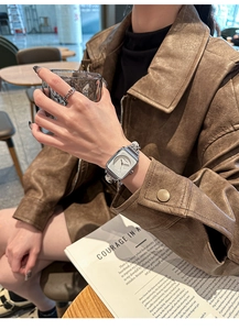 Close-up of a silver square face watch with metal chain strap on woman's wrist