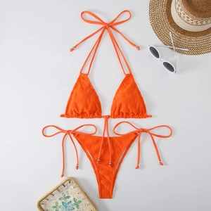 Flat lay of bright orange textured bikini set with summer hat and sunglasses accessories