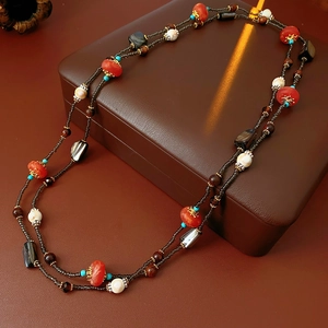 Détail du collier bohème avec perles en bois et coquillages sur boîte en cuir