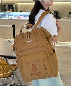 Side view of khaki large capacity school backpack with bear embroidery on female model