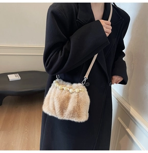 Detail of faux fur bucket bag featuring a beaded handle and long shoulder strap